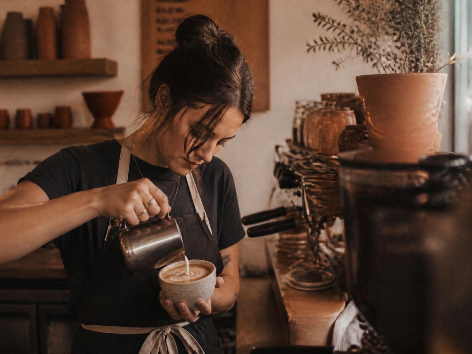 Barista pouring latte art at the Bean Theory bar